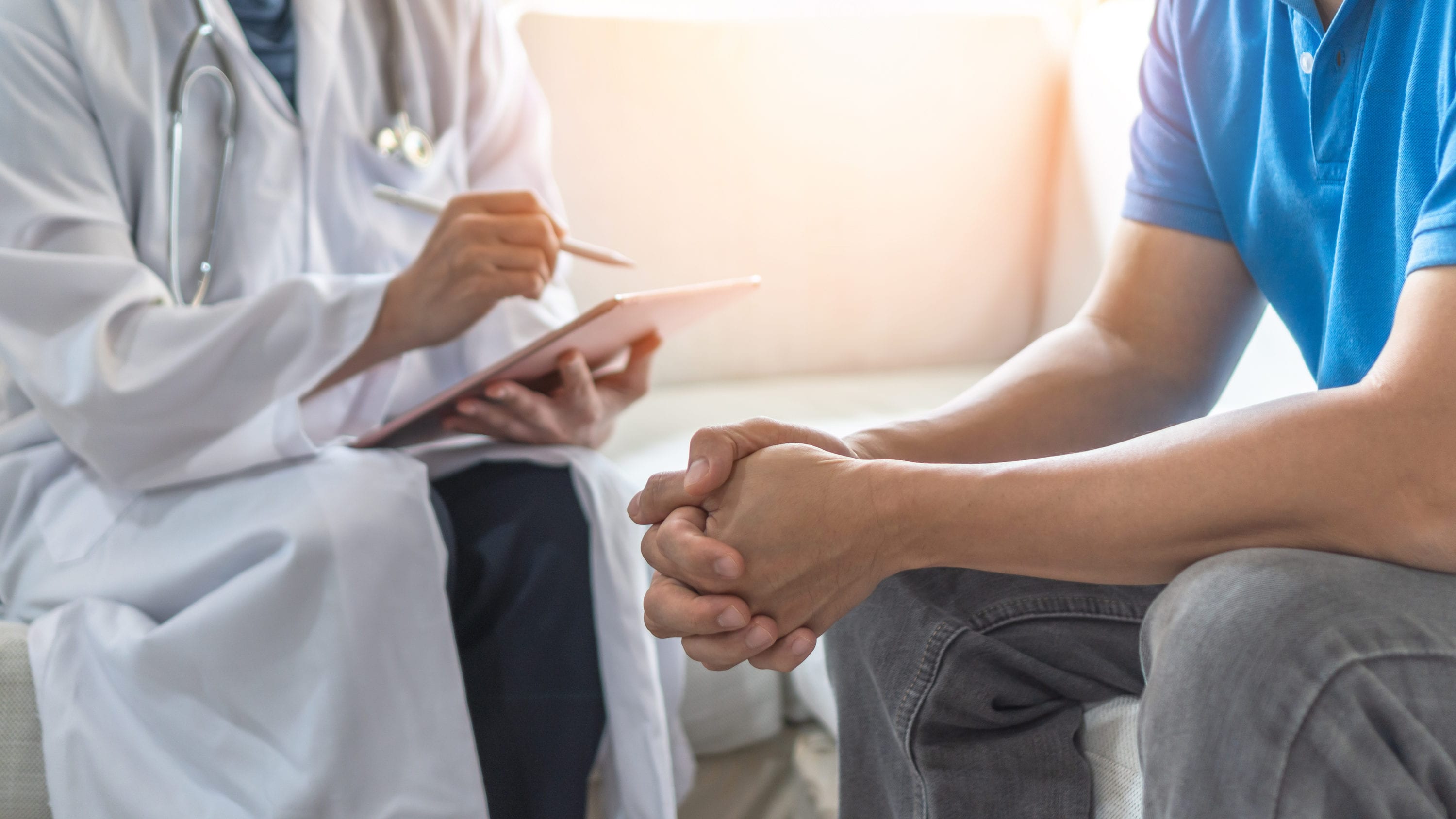 Avkapad bild på läkare som sitter ner med en man och går igenom formulär vid en undersökning för företagshälsa